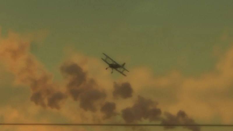 Un avion biplan Duster de couleur jaune survolant des champs.